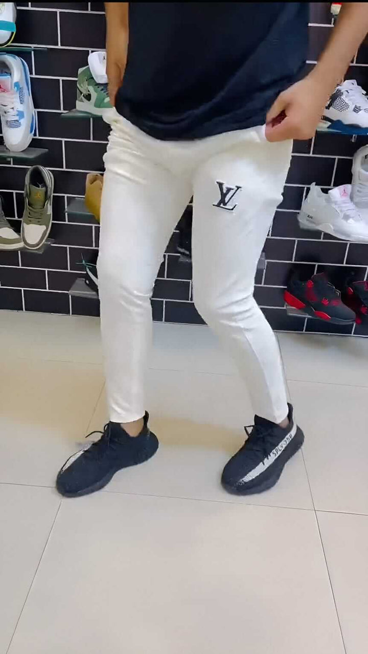 Person wearing LV Signature Luxury Trouser styled with black shoes in a fashionable sneaker display.